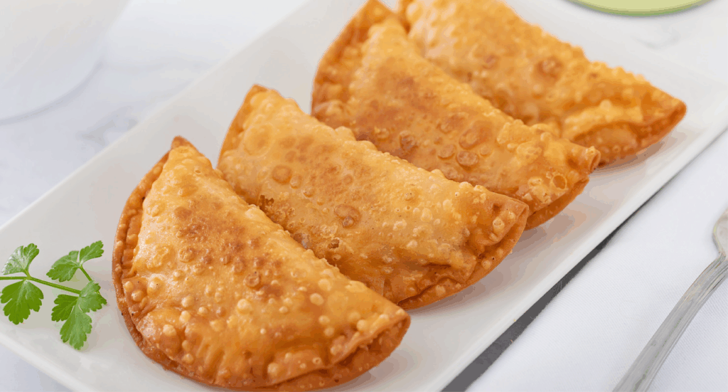 Empanadillas fritas doradas servidas en un plato.